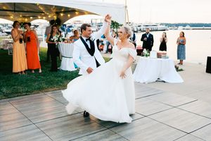 Wedding guests dance together on an outdoor patio during a sunset reception celebration.