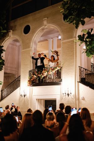 Wedding guests gather with phones raised to capture a special moment on an elegant staircase at an indoor venue.