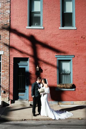 Wedding couple poses against a red brick wall with blue trim windows in a series of progressive shots.
