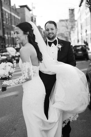 A black and white wedding photo series showing a bride in a white dress and groom in a tuxedo walking on a city street.