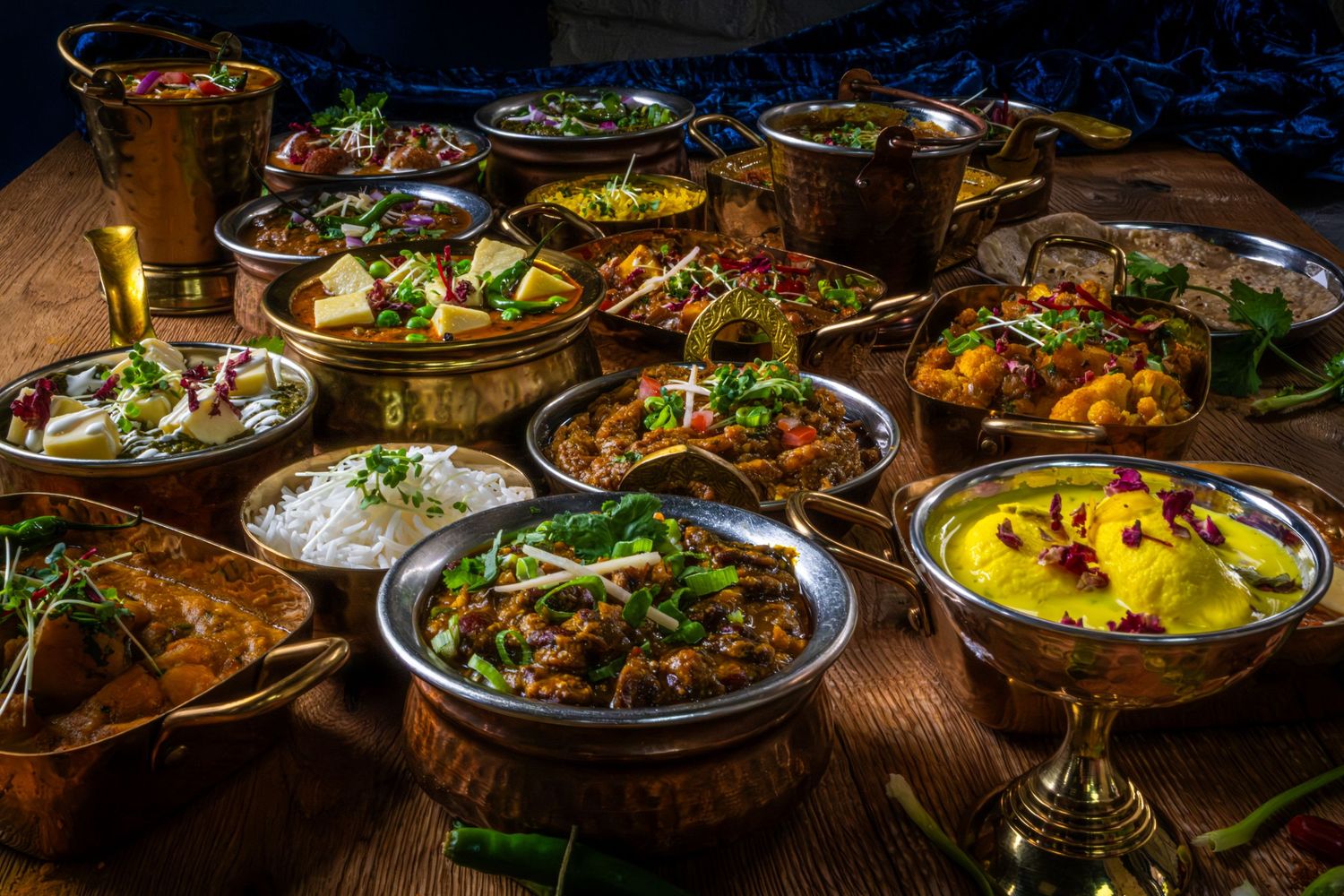 A vibrant selection of delicious curry dishes served in bowls, rich sauces, fresh herbs, and colourful spices. Restaurant menu photography
