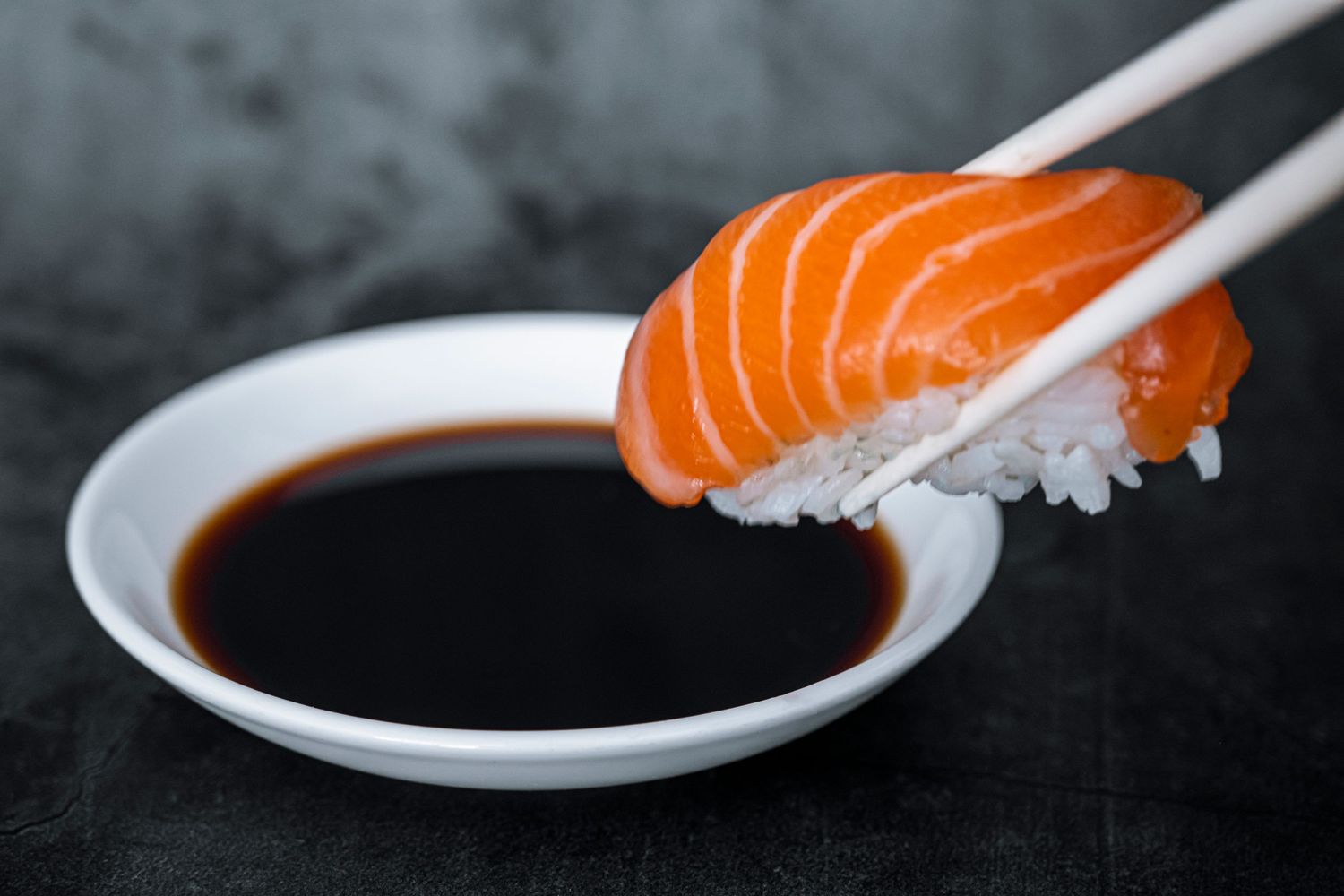 Close-up of fresh salmon sushi with glossy slices and wasabi, captured in natural light with a softly blurred background for focus.
