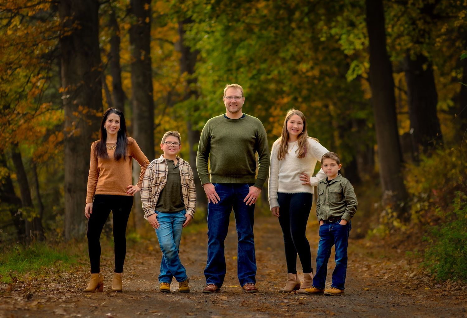gorgeous fall family photo of a family posing along a tree lined walkway