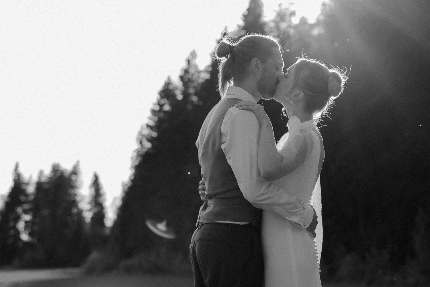 A black and white wedding portrait of a newlywed couple in formal attire gazing at each other outdoors.