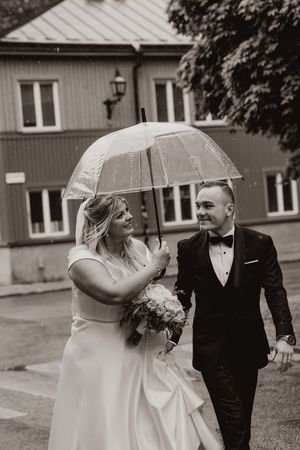 Brudpar under paraply på södermalms gator i spöregn