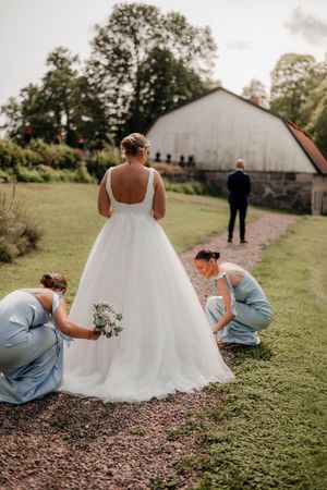 Brudens brudtärnor fixar hennes brudklänning inför firstlook