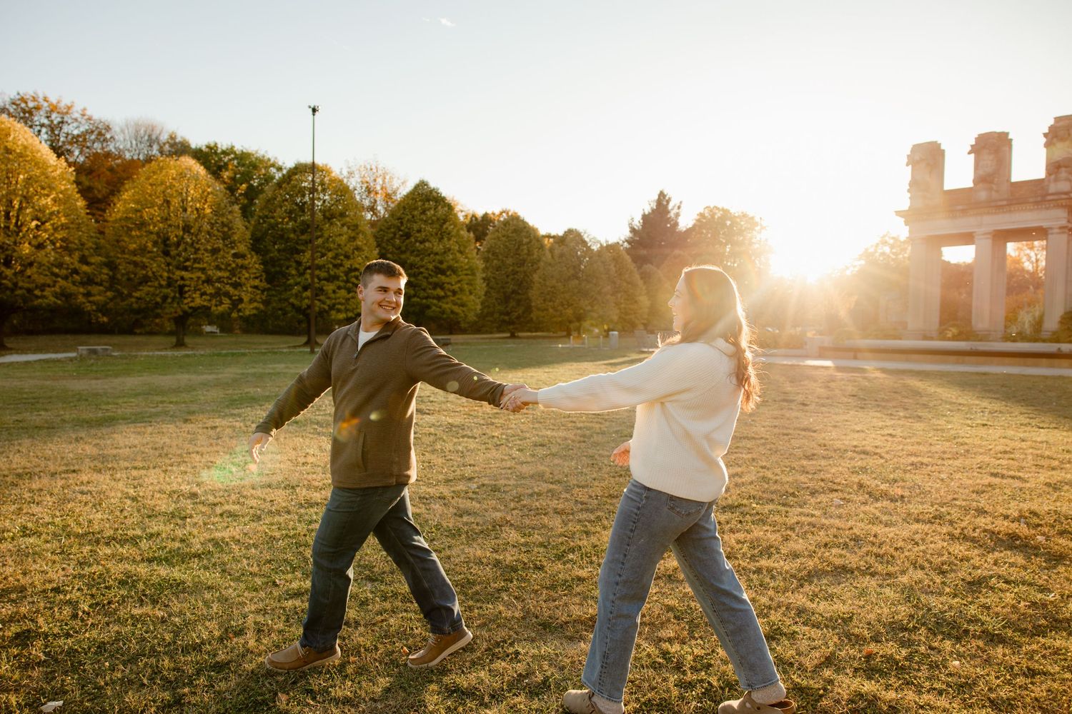 People playing and running in a grassy field at sunset.