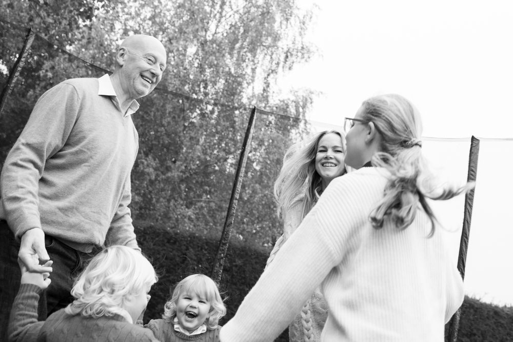 A black and white photo showing candid moments of people laughing and embracing at a family gathering in Cambridgeshire.