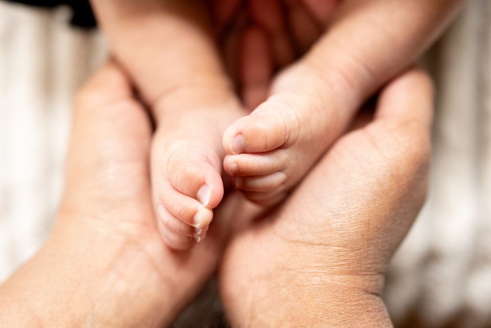 A tiny baby's hand gently grasps an adult's finger in a tender moment of connection.