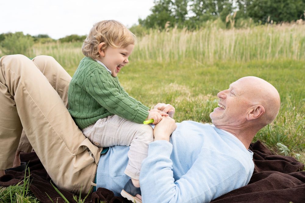 A pair relaxes together in a sunny meadow with tall grass and wildflowers.