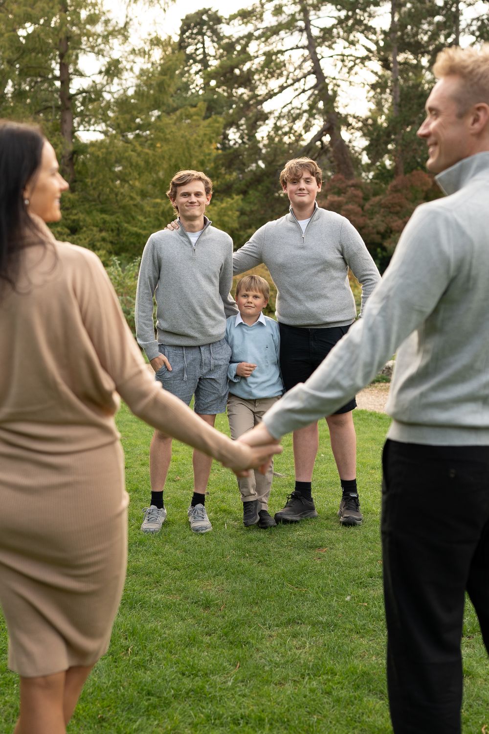 A  family photo showing people in casual attire gathering on a grassy lawn outdoors during daytime.