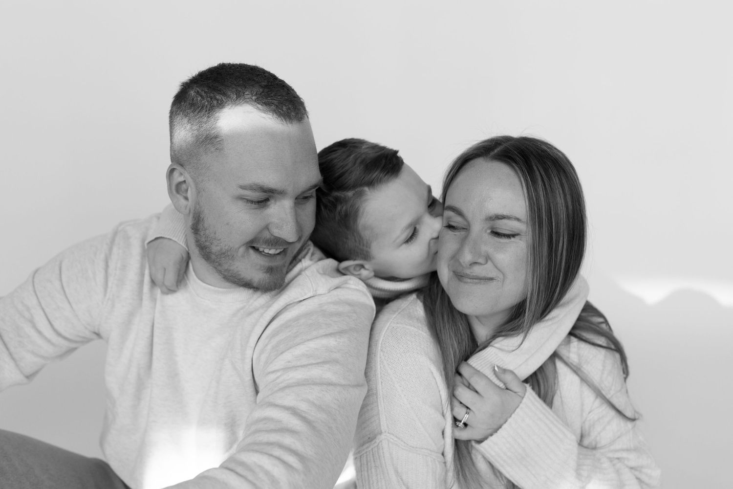 An intimate black and white family portrait showing a tender moment.