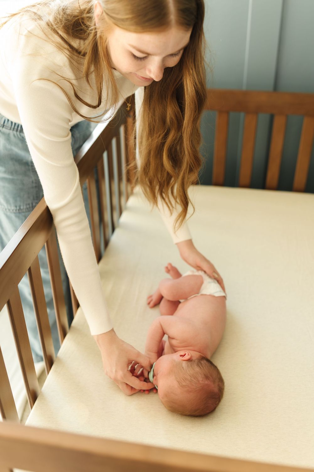A tender moment between parent and baby in a wooden crib as they share gentle interaction and bonding time.