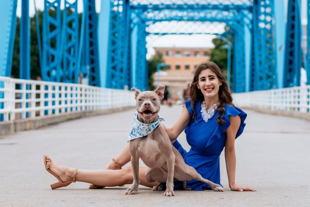Dog and companion pose on blue bridge during outdoor photoshoot.