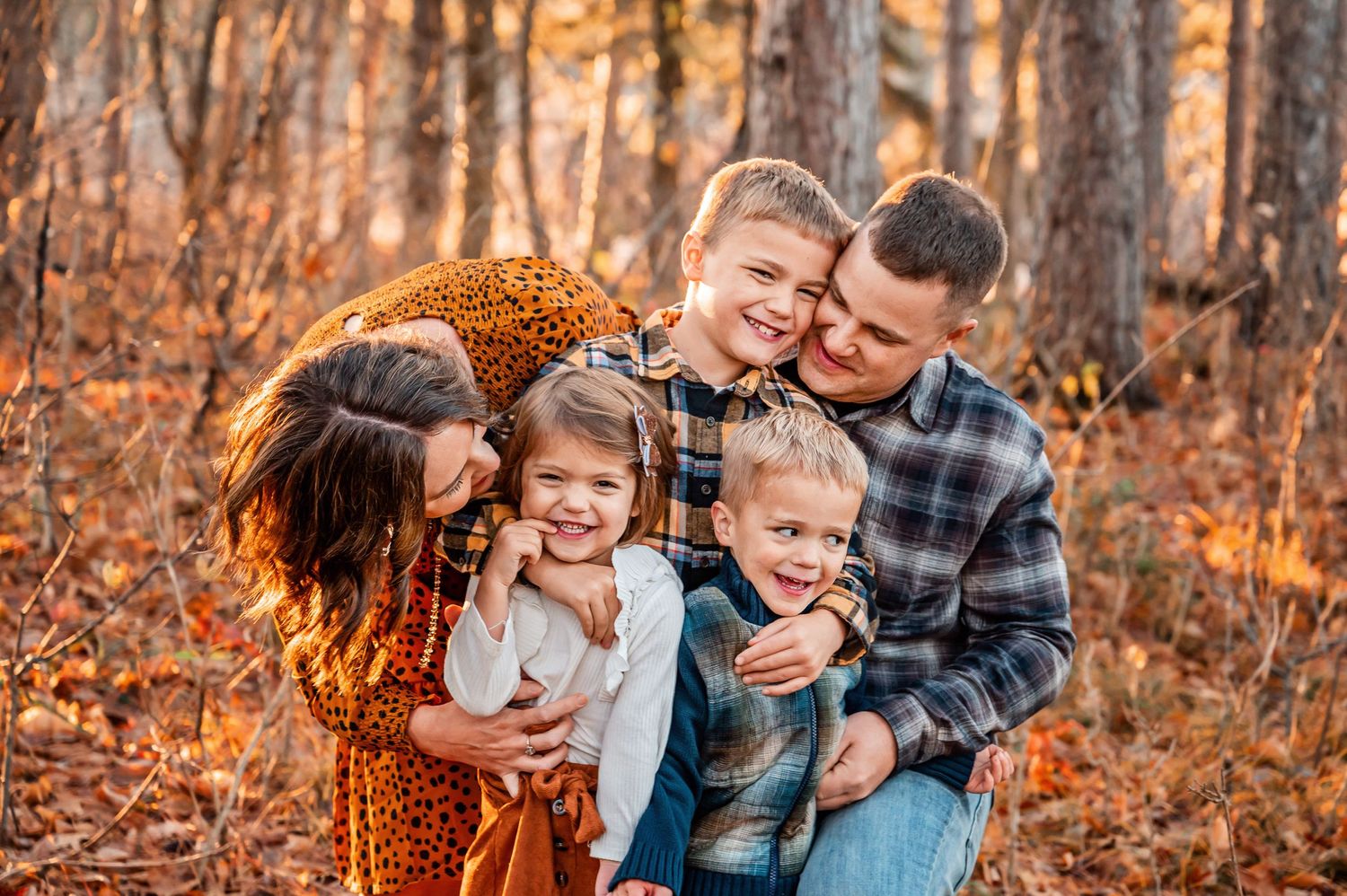 Family embracing while enjoying a warm autumn day in the woods with fall foliage.