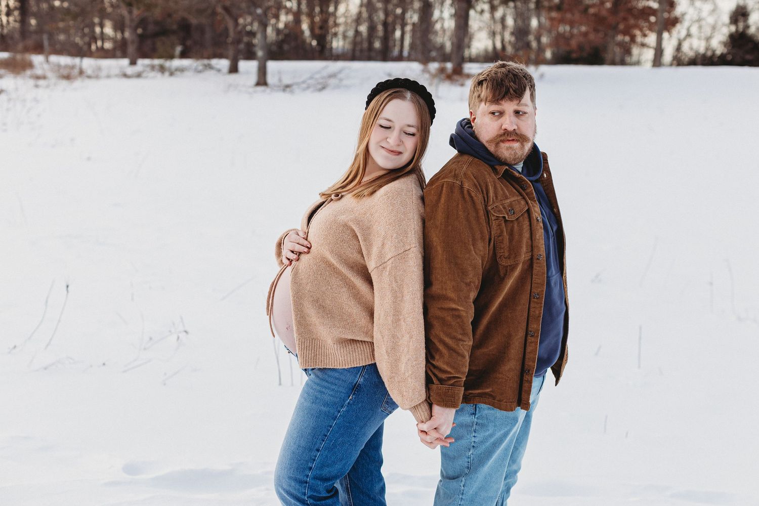 Maine winter maternity session featuring couple in snow capturing intimate pre-baby moment