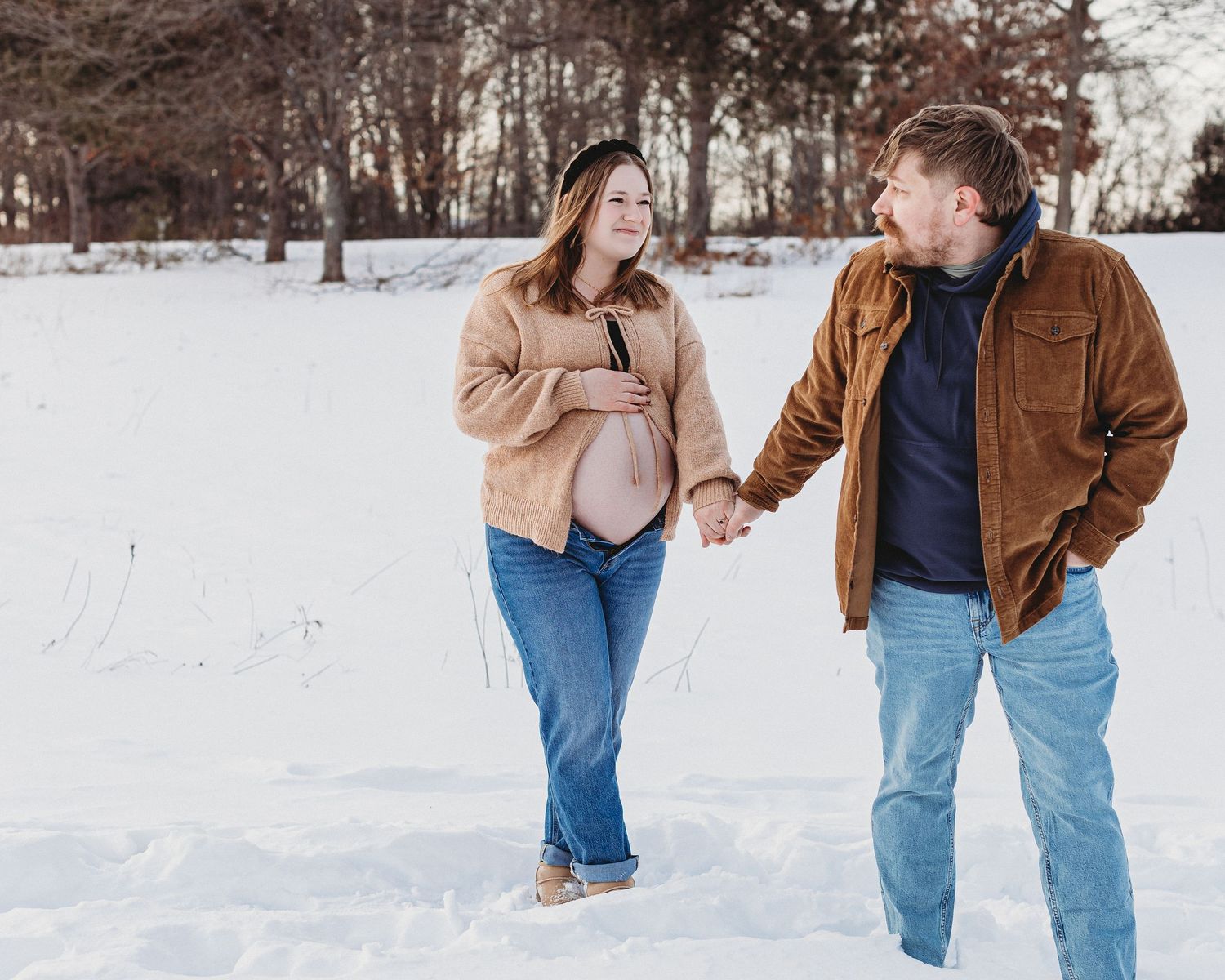 Expecting couple winter maternity shoot in Maine with snowy forest and warm, candid moment