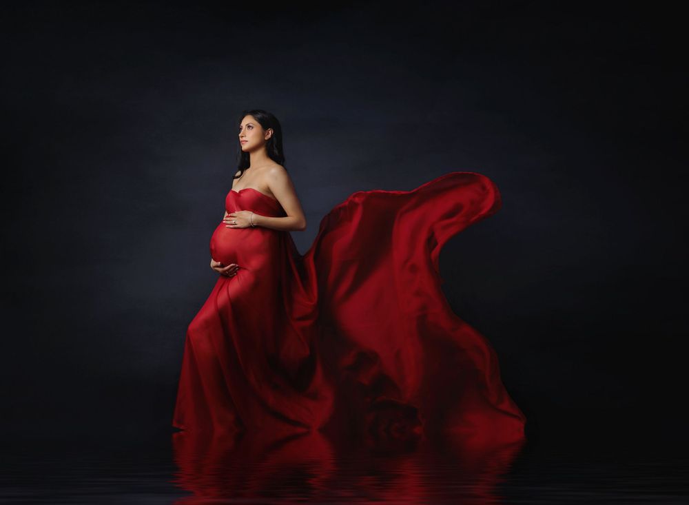 Fine art studio maternity portrait featuring flowing red gown photographed by Austin maternity photographer