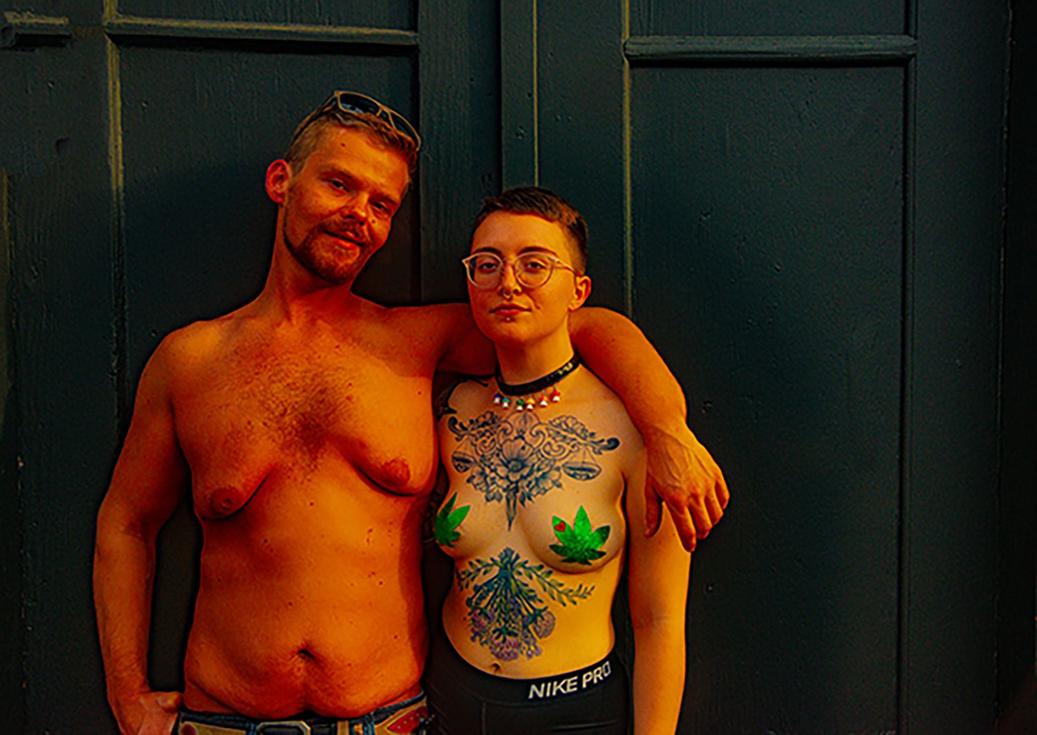 Group photo against dark wall showing people with tattoos in casual attire.