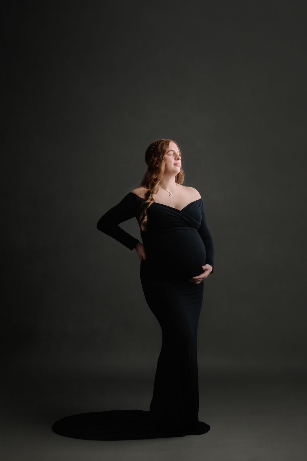 maternity studio photo session dark backdrop mom to be holding belly