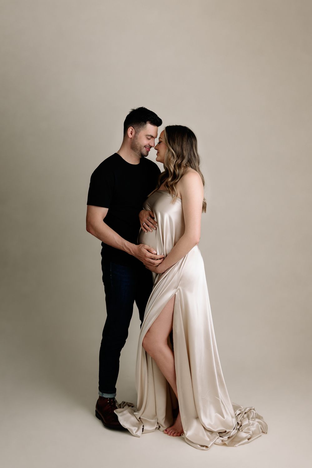 maternity studio photos couple posed on beige backdrop in raytown portrait studio