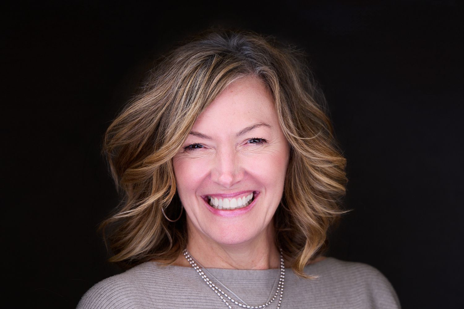 Portrait of person with short brown hair and natural makeup outdoors.