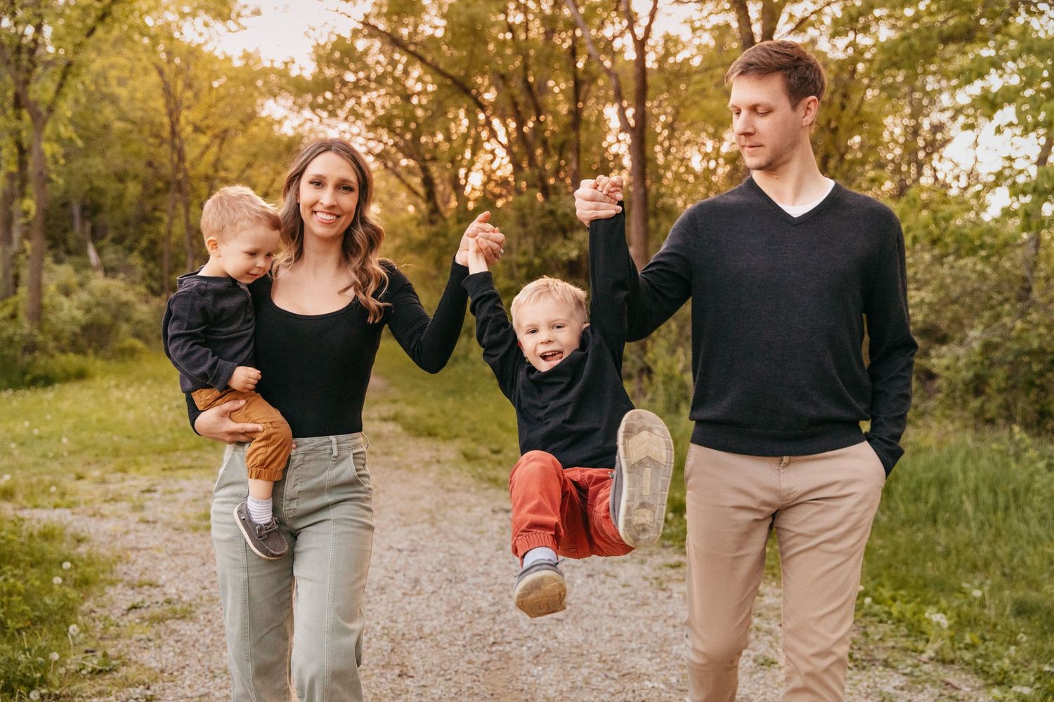 A family with two young kids smiles while walking together in Lakeville near Prior Lake, MN for family photos