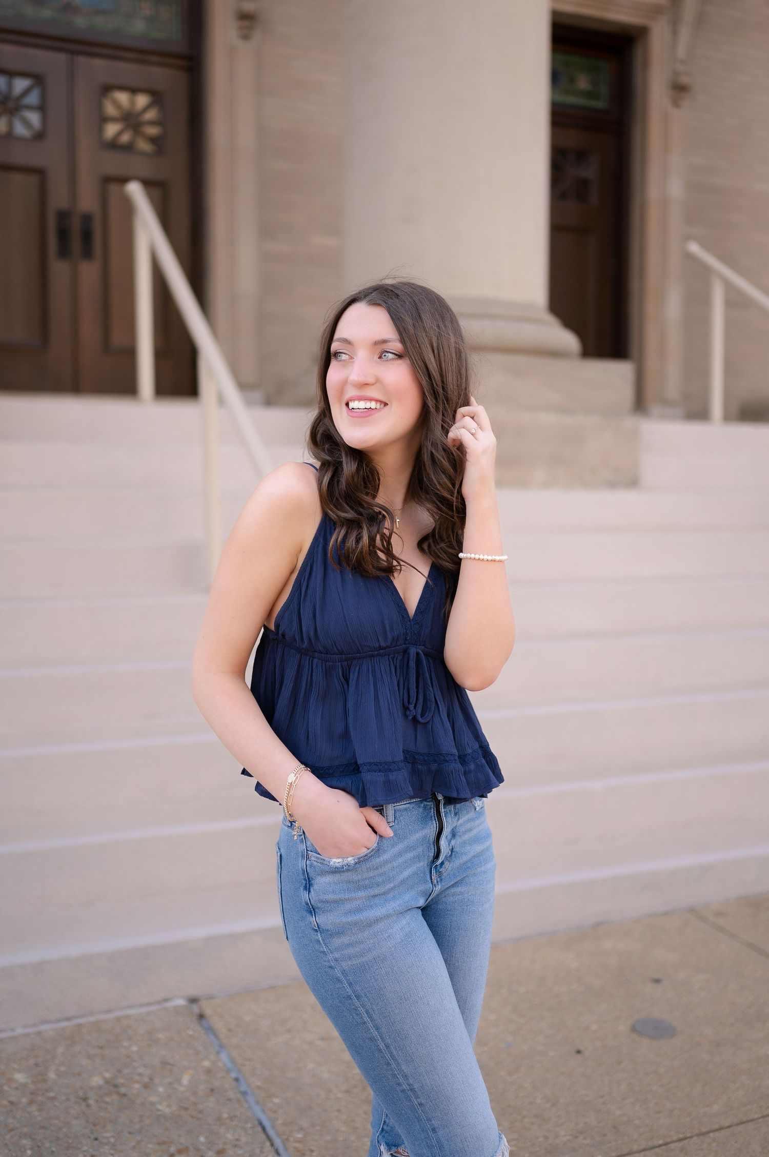 Casual outdoor portrait in navy sleeveless top and fitted jeans.