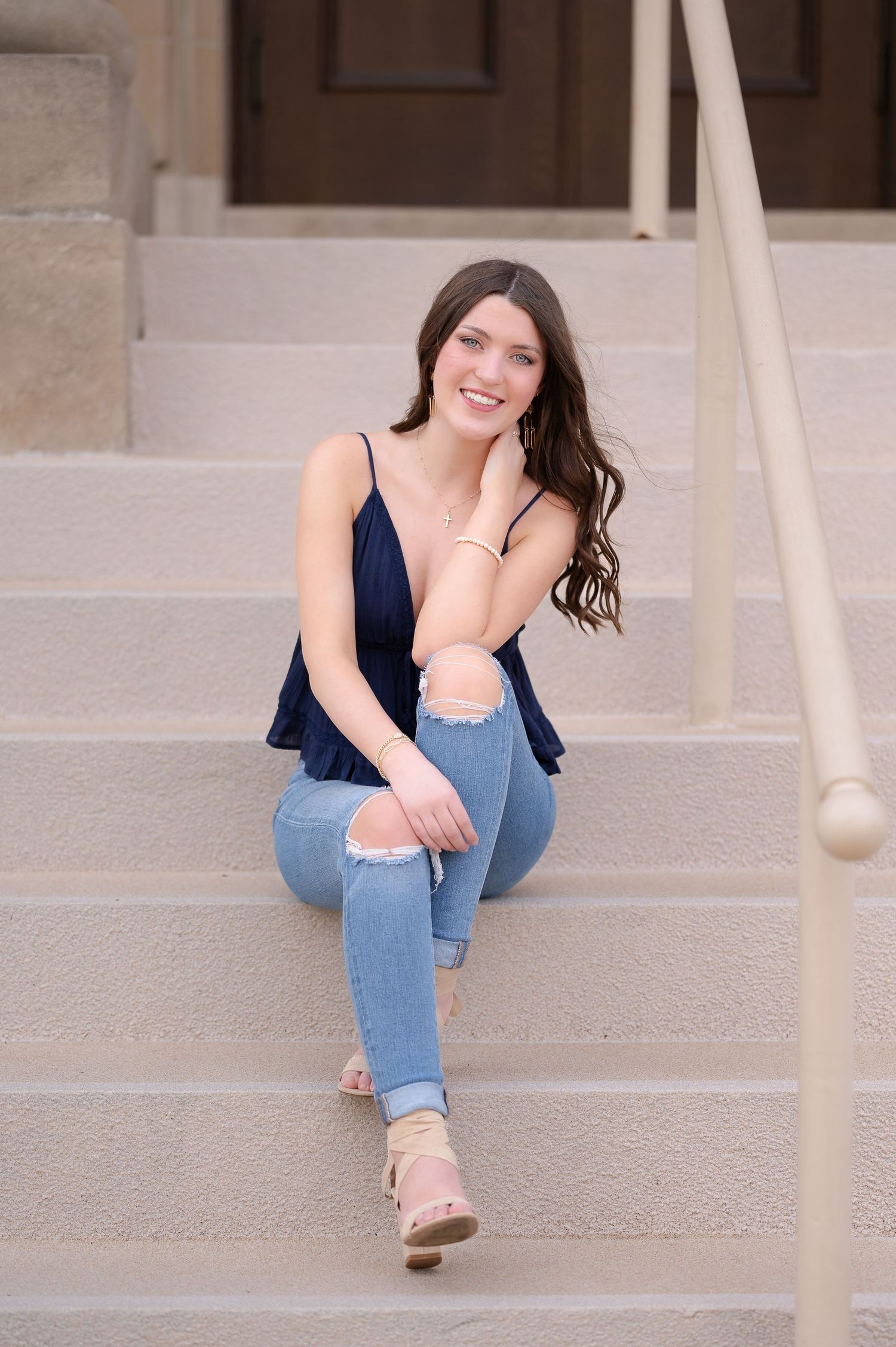 Casual portrait on concrete steps with navy top and distressed jeans.
