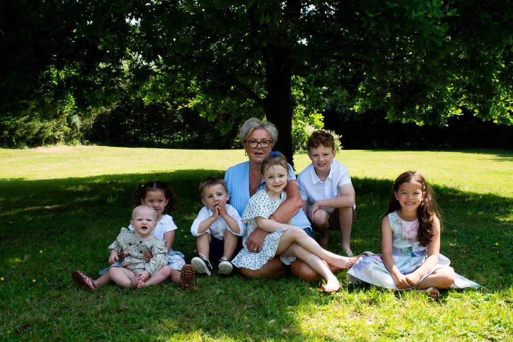 Extended family enjoying a relaxing summer day together on the lawn with matching blue outfits in a garden setting.