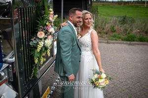 Newlyweds pose together in front of decorative greenery and flowers.