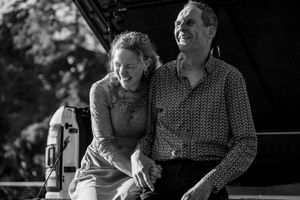 A black and white image capturing intimate moments between guests at an outdoor event.
