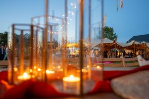 Row of glowing candles in glass holders creating atmospheric lighting at dusk.