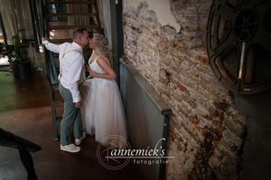 Wedding couple sharing intimate moment against rustic brick wall background.