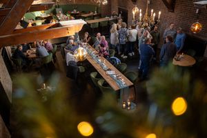 Warm candlelit ambiance at an indoor reception with guests mingling in the background.