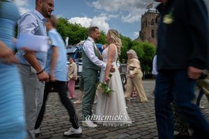 Wedding guests gather outside on cobblestone pavement during a sunny afternoon celebration.
