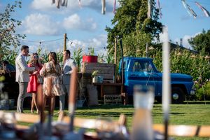 Outdoor garden party setting with decorative string lights and blue sky.