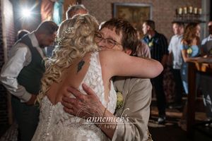 Emotional dance floor moment captured during wedding reception in dimly lit venue.