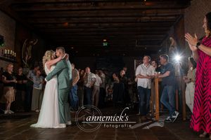 Wedding reception dance floor scene with dramatic lighting and exposed wooden beams.