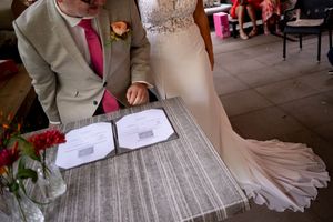 Bride and groom signing official wedding documents at a decorated table during their marriage ceremony.