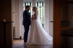 Elegant wedding ceremony setup in front of large windows with natural light streaming in.