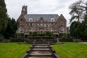 Exterior view of a grand stone mansion with manicured grounds and steps.