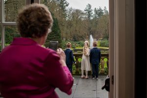 View through a window frame of guests gathering outside a stately building.