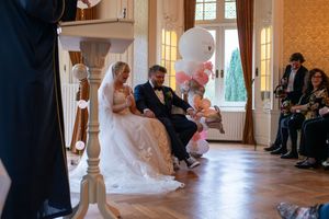 Wedding ceremony taking place in an elegant indoor venue with natural light streaming through windows.