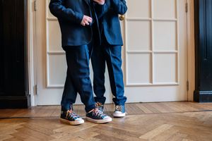 Close-up of formal shoes and pant legs on a hardwood floor.