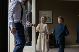 Wedding preparations in a bright room with white bedding and natural window light.