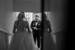 Silhouetted figures in formal wear walking through an elegantly lit hallway.