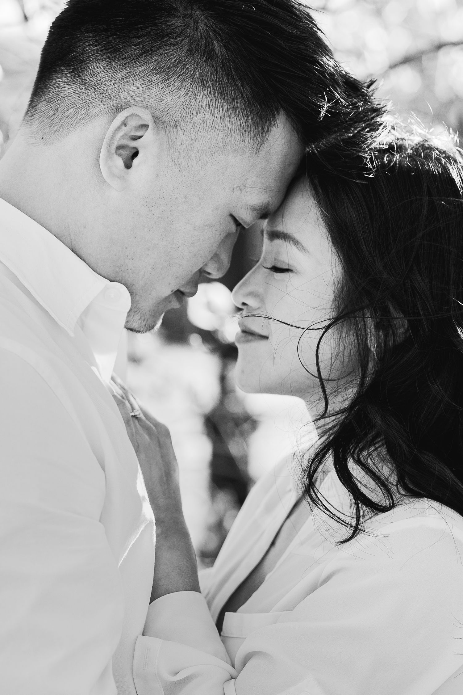 Intimate black and white portrait of a couple sharing a tender romantic moment with their faces close together.