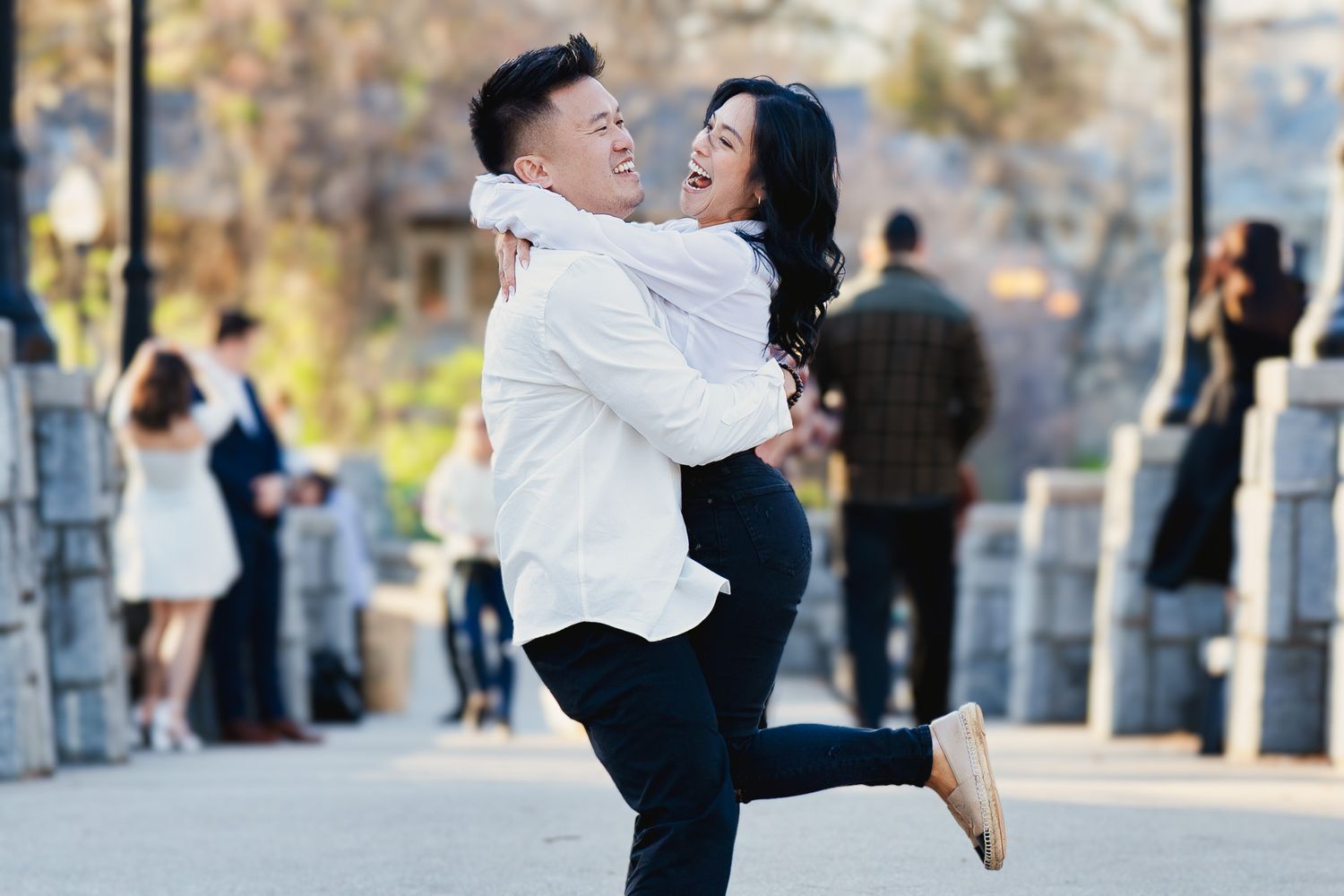 A couple in white and black attire embrace and dance together outdoors during a celebration.