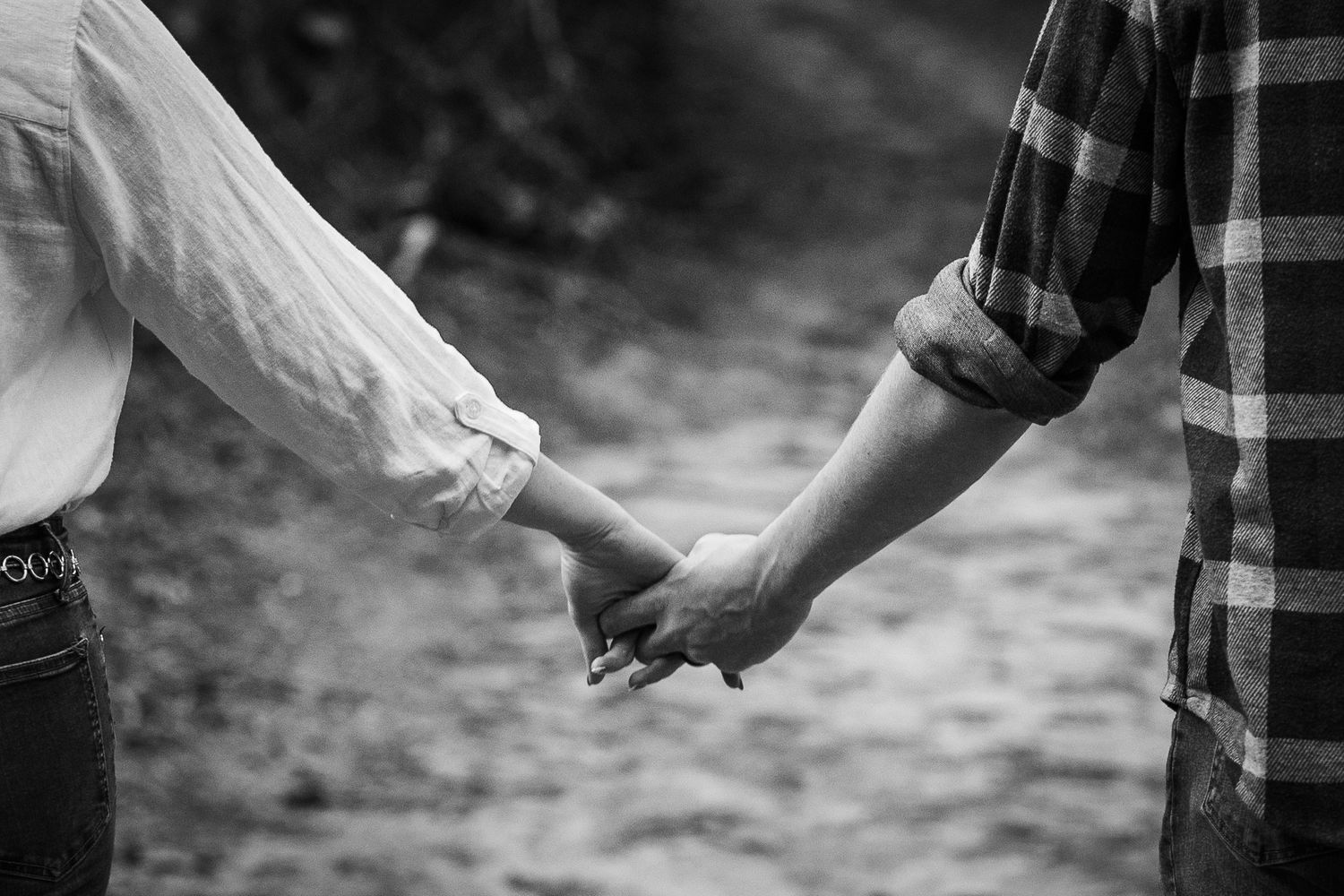 Black and white close-up photo of hands holding each other in an emotional gesture.